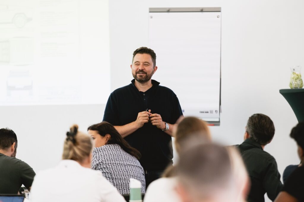 Wat is crossmediale communicatie en waarom heeft jouw bedrijf het nodig? 1 Ondernemers coach geeft een presentatie voor een groep mensen.